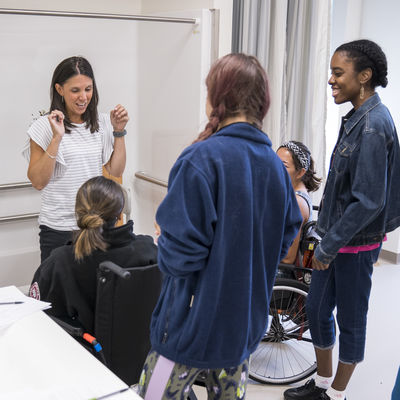 Kim Pachik, occupational therapy program director, speaks with five students in an Activities of Daily Living (ADL) suite classroom