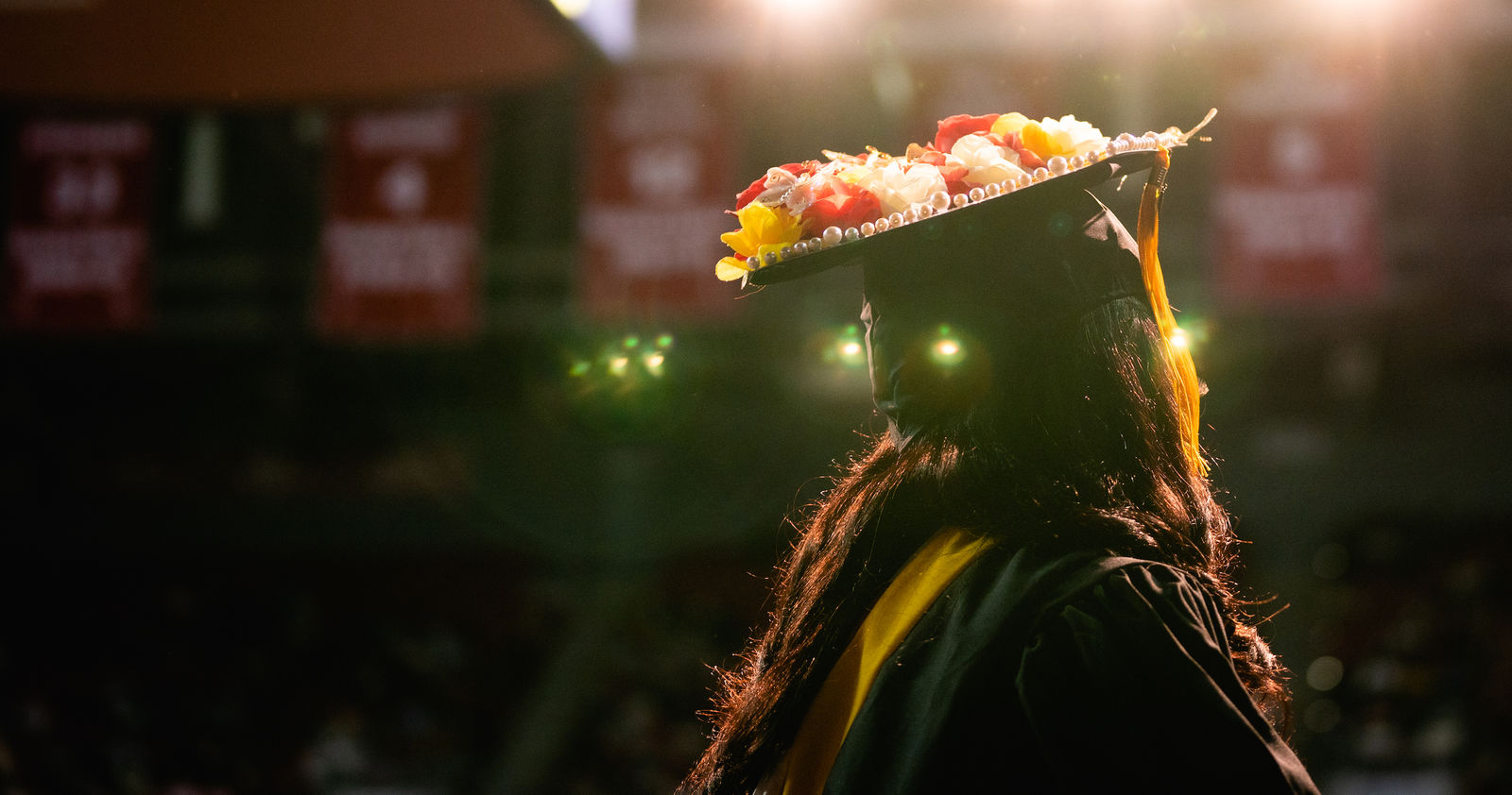 a student wearing a graduation cap stands in front of the crowd in the Liacouras Center