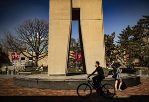 a student rides their bike by the bell tower