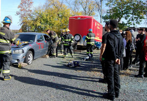 EMT students observe emergency workers demonstrate how to rescue injured persons in a car following an accident 