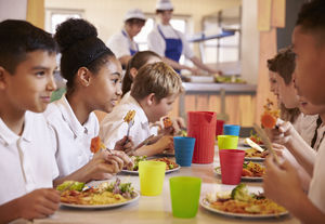 children sitting at a school cafeteria table eating lunch