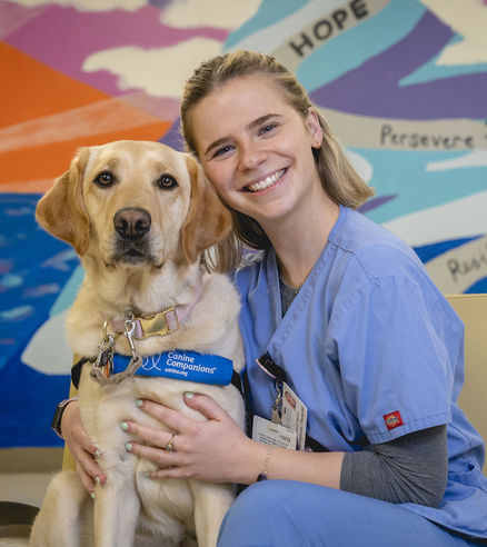 Alumna Jessica Hetrich hugging her yellow lab, Wellie