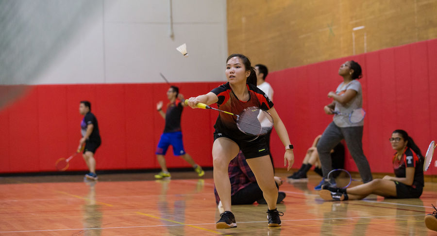 Students in a gym playing badminton