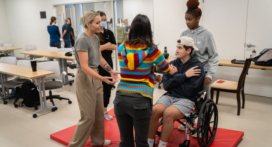 Students learn to safely move a patient in a wheelchair