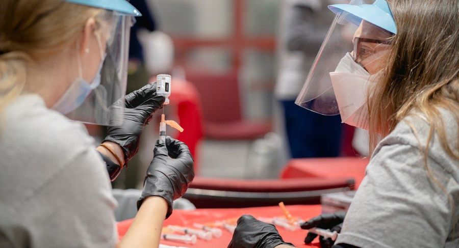 a student and professor prepare syringes for covid-19 vaccine