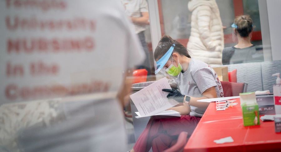 a student sitting down reads information about covid-19 vaccine