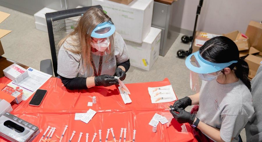 a student and professor prepare syringes for covid-19 vaccine