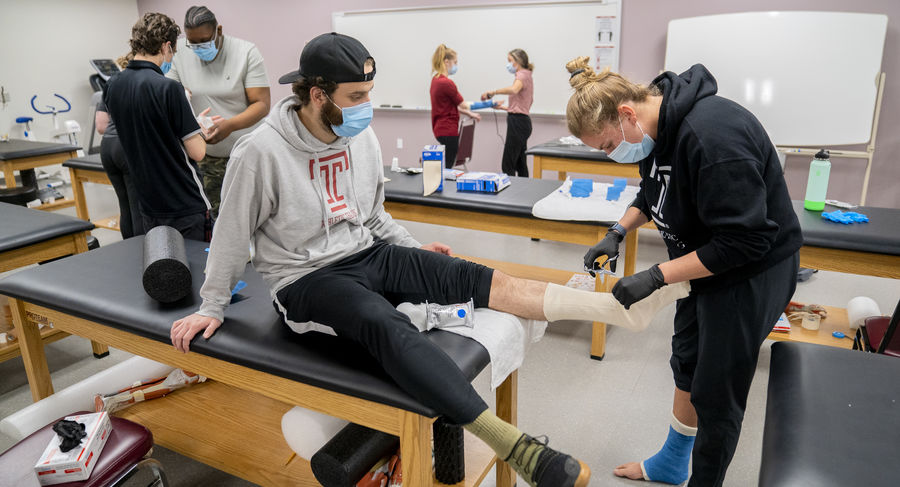 An athletic training student practices casting another student's foot