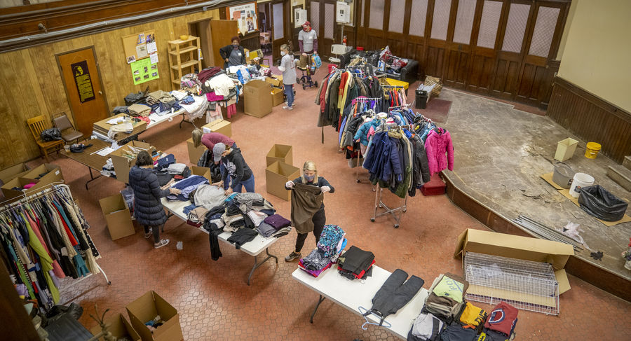 Overhead view of people in a large room sorting clothing on racks and tables
