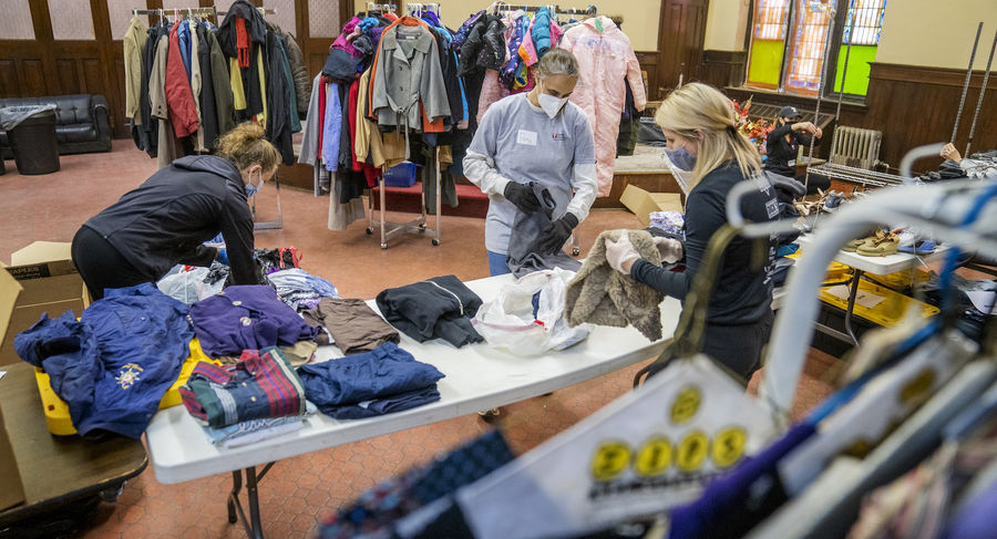 Three people sorting through piles of donated clothes