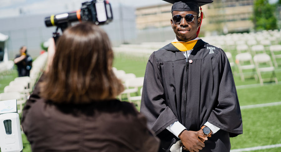 a student poses for a photo after crossing the graduation stage