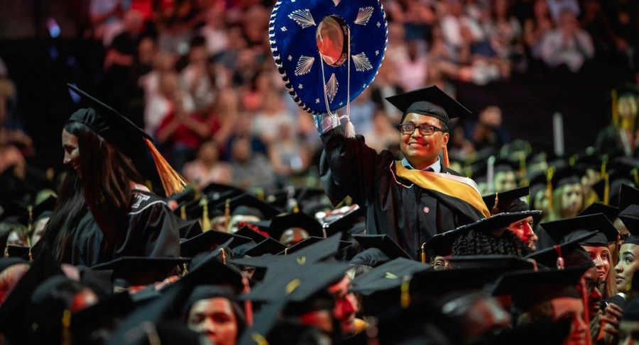 A student waves a hat in the crowd at graduation.