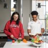 Two students at a cutting board chopping veggies