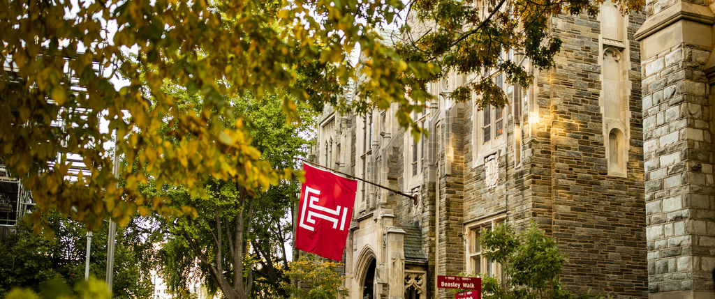 a temple flag waves on campus as students walk by