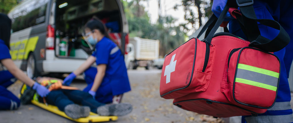 an EMT walks toward the scene of an accident with a medical bag in hand
