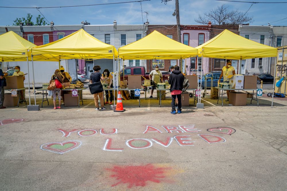 a row of tents at an outdoor vaccine clinic. The words "you are loved" is spray-painted on the ground in front of them