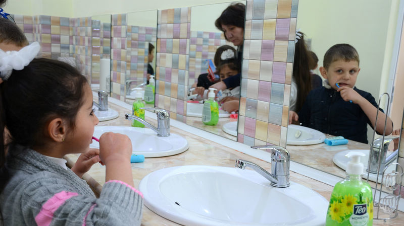 Child using a mirror while brushing teeth 