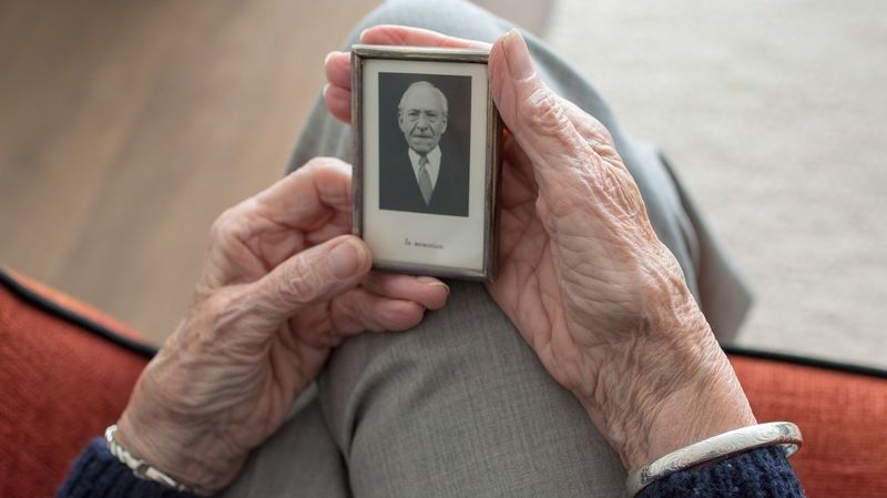 Elderly person holds old photograph of man