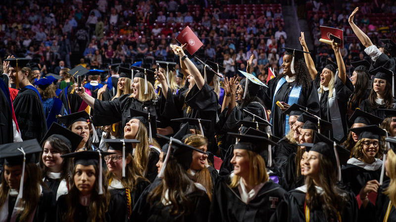 Group of graduates in cap and gown celebrating in the Liacouras Center