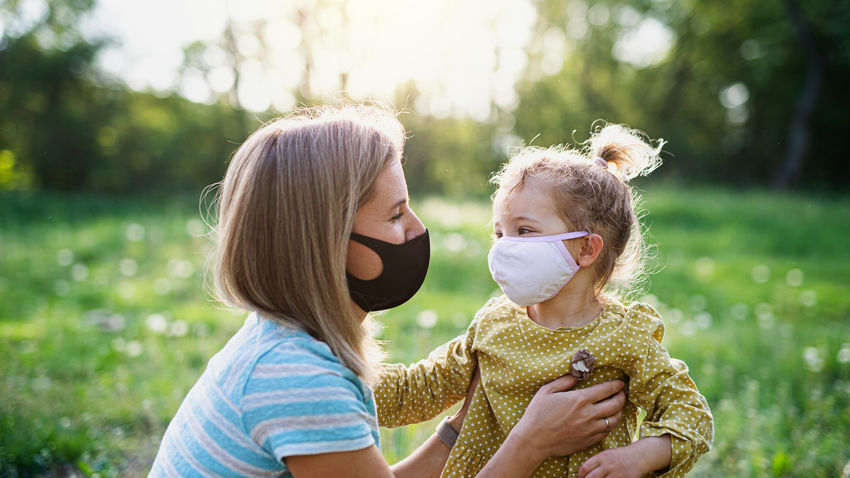 a woman speaks to her young child in a park