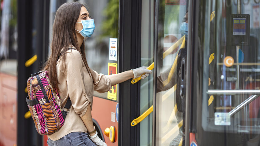 a woman wearing a face mask boards a public transit bus