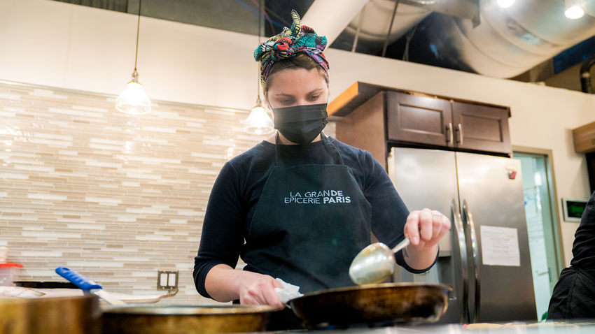 a student practices a basting technique in a skillet