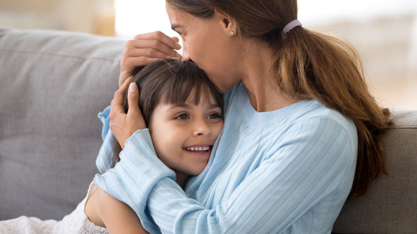 a mother kisses her smiling child