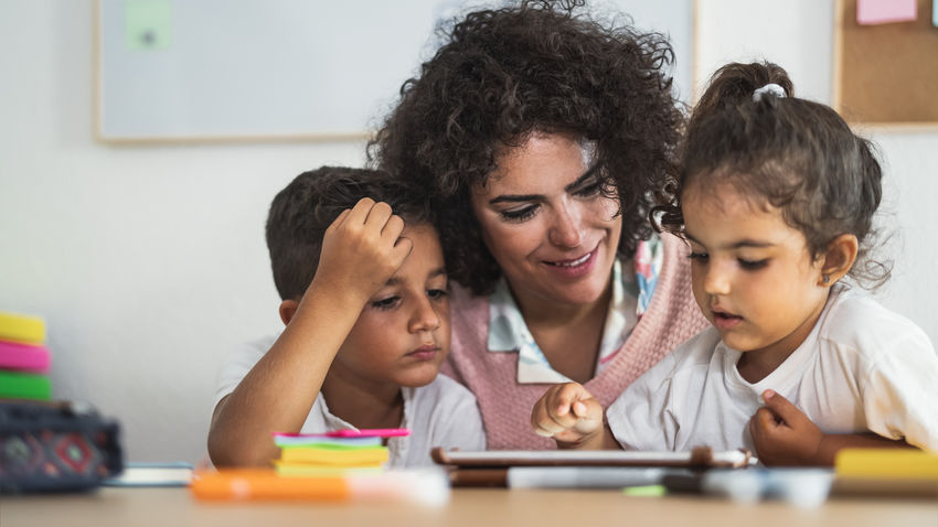 a woman works in a classroom with two children