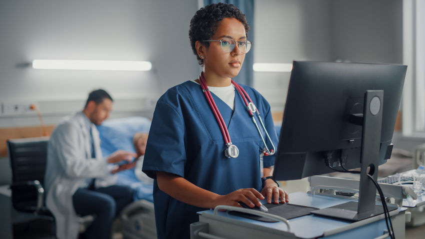 a nurse enters data at a computer