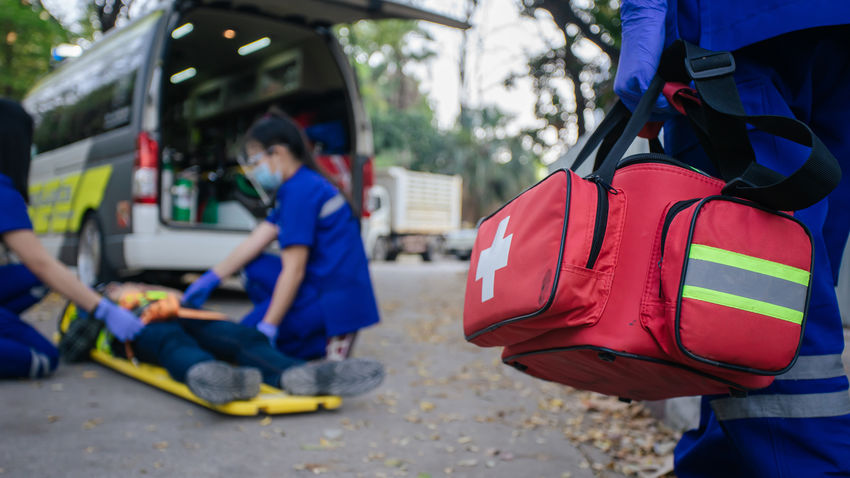 an EMT walks toward the scene of an accident with a medical bag in hand