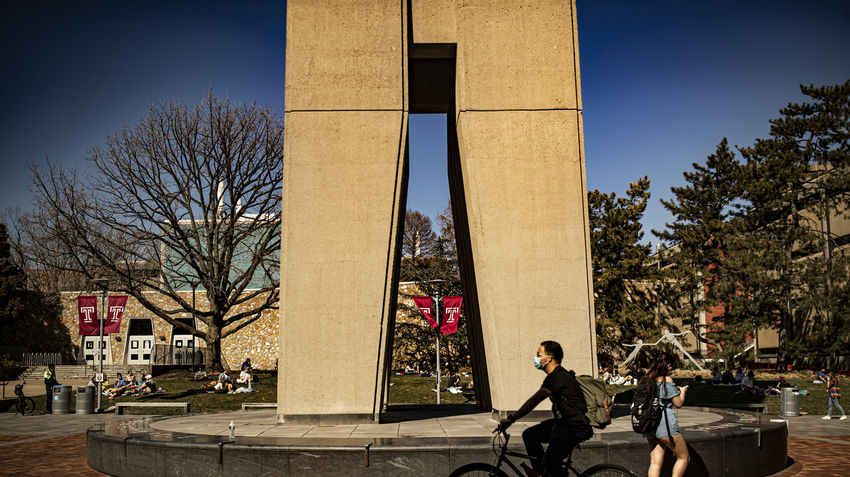 a student riding a bike in front of the belltower