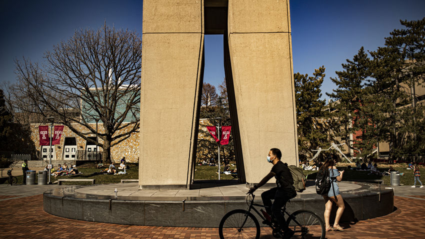 a student rides their bike by the bell tower