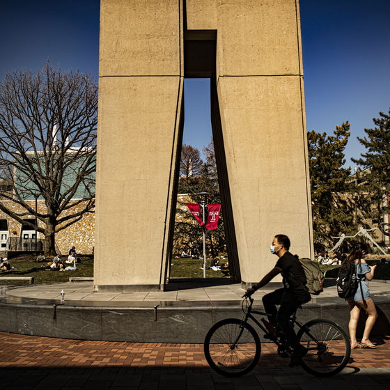 a student riding a bike in front of the belltower