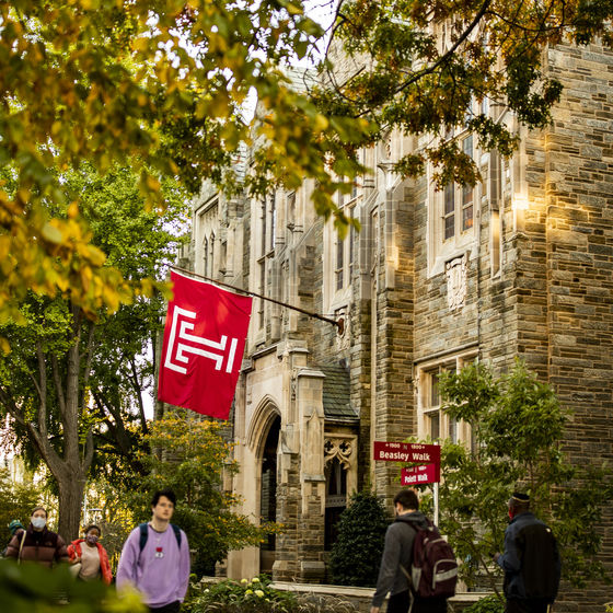 a temple flag waves on campus as students walk by