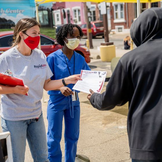 students handing out a flyer in a philadelphia neighborhood