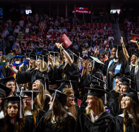 Group of graduates in cap and gown celebrating in the Liacouras Center