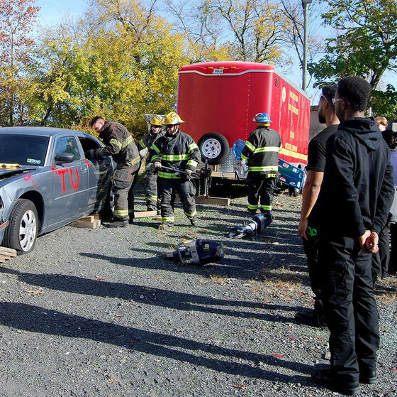 EMT students observe emergency workers demonstrate how to rescue injured persons in a car following an accident 