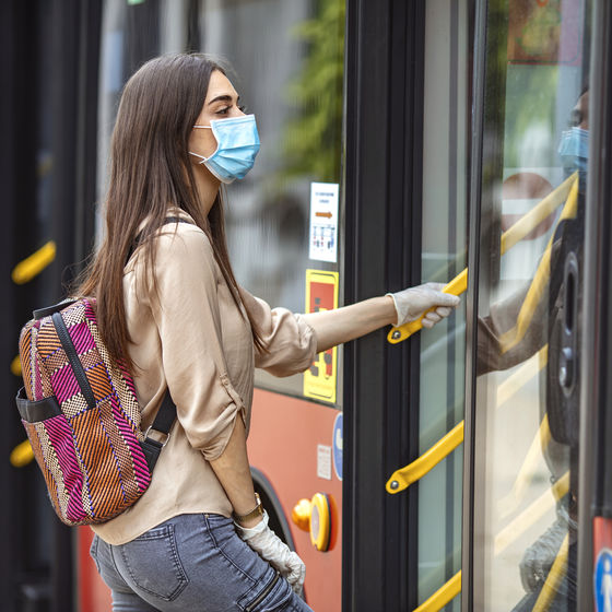 a woman wearing a face mask boards a public transit bus