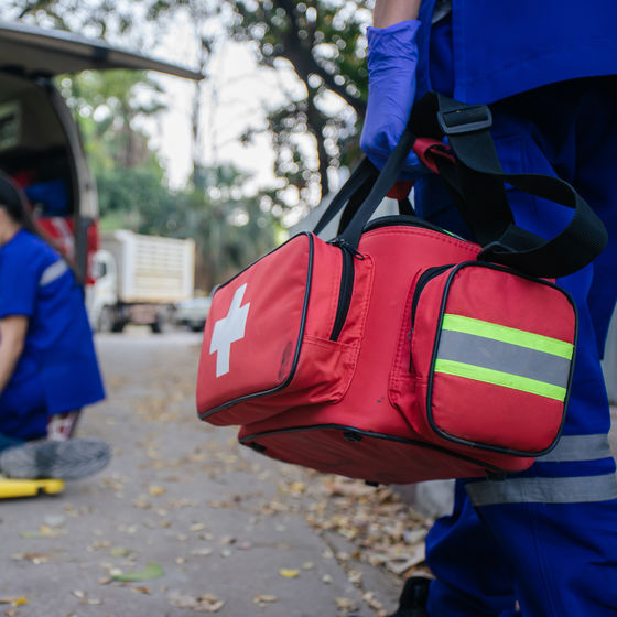 an EMT walks toward the scene of an accident with a medical bag in hand