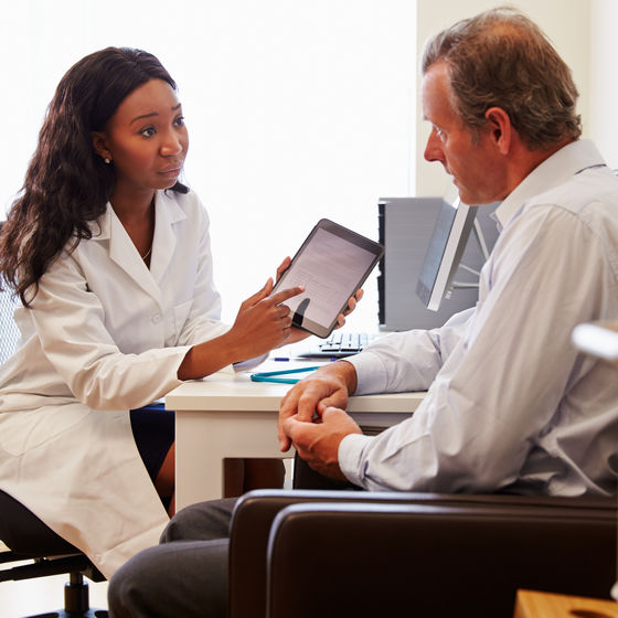 a doctor shows a patient information on a tablet
